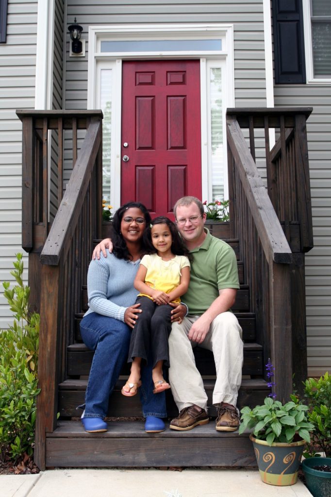 Family sitting in front of House