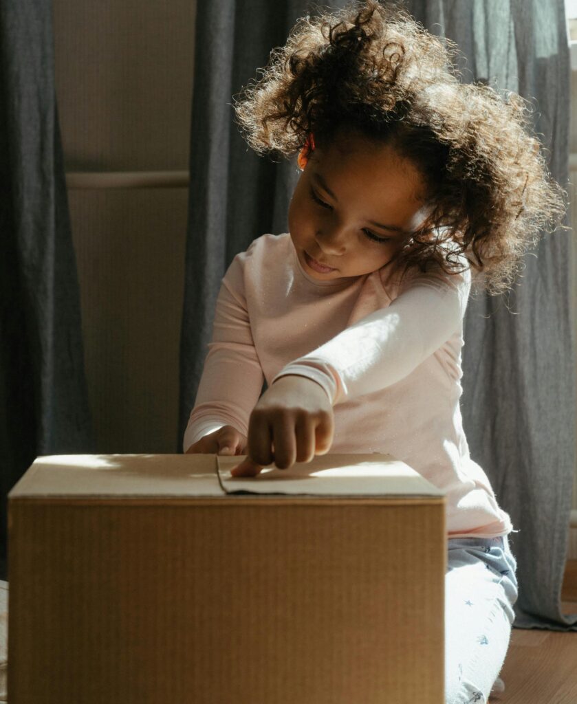 Child helping pack moving boxes during a family home sale.