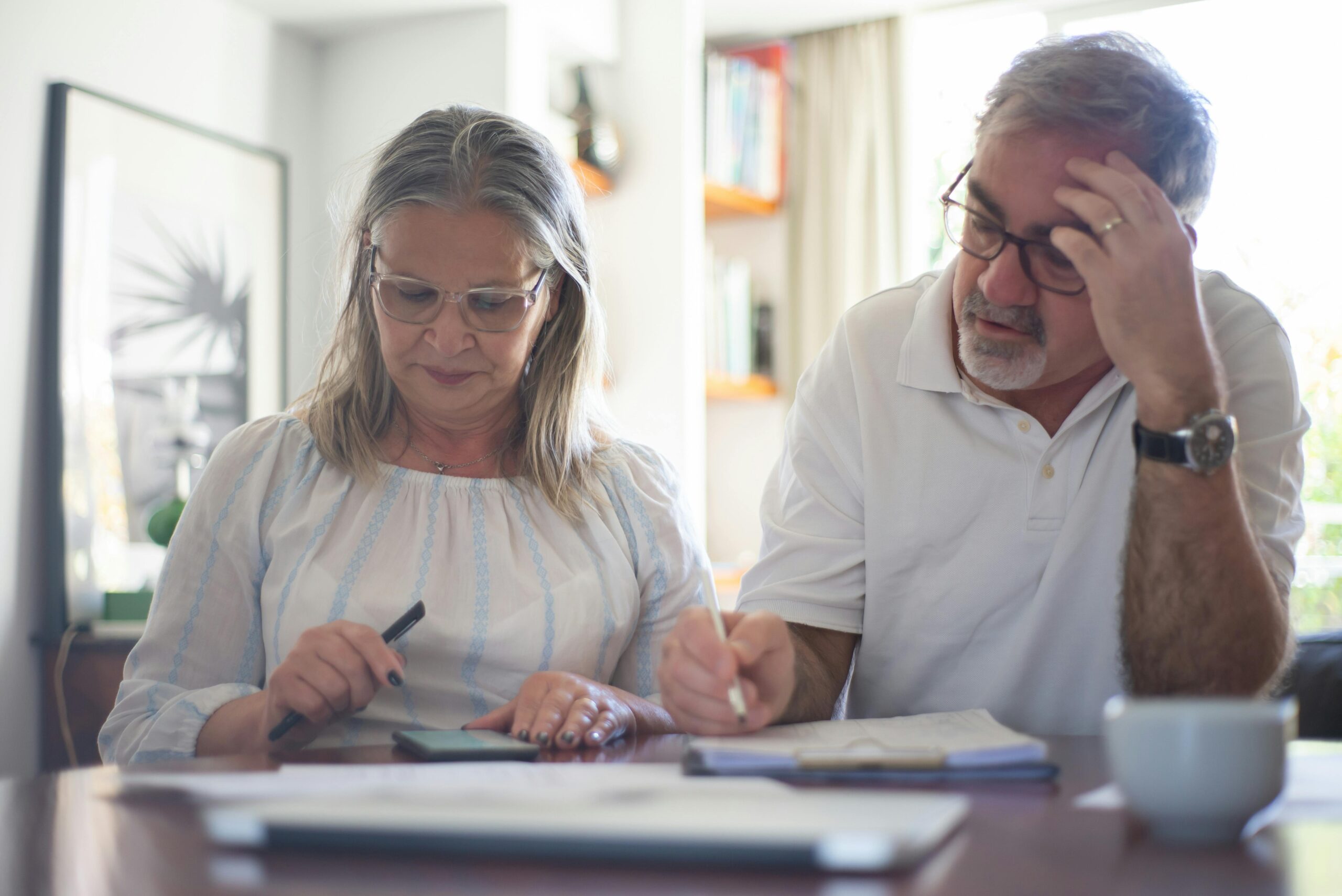 Mature couple reviewing floor plans while deciding to rent or buy after downsizing in Ontario"