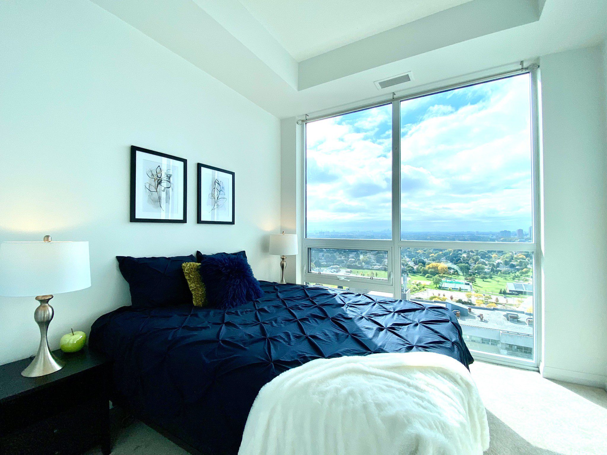 Bright primary bedroom with floor‑to‑ceiling windows & view.