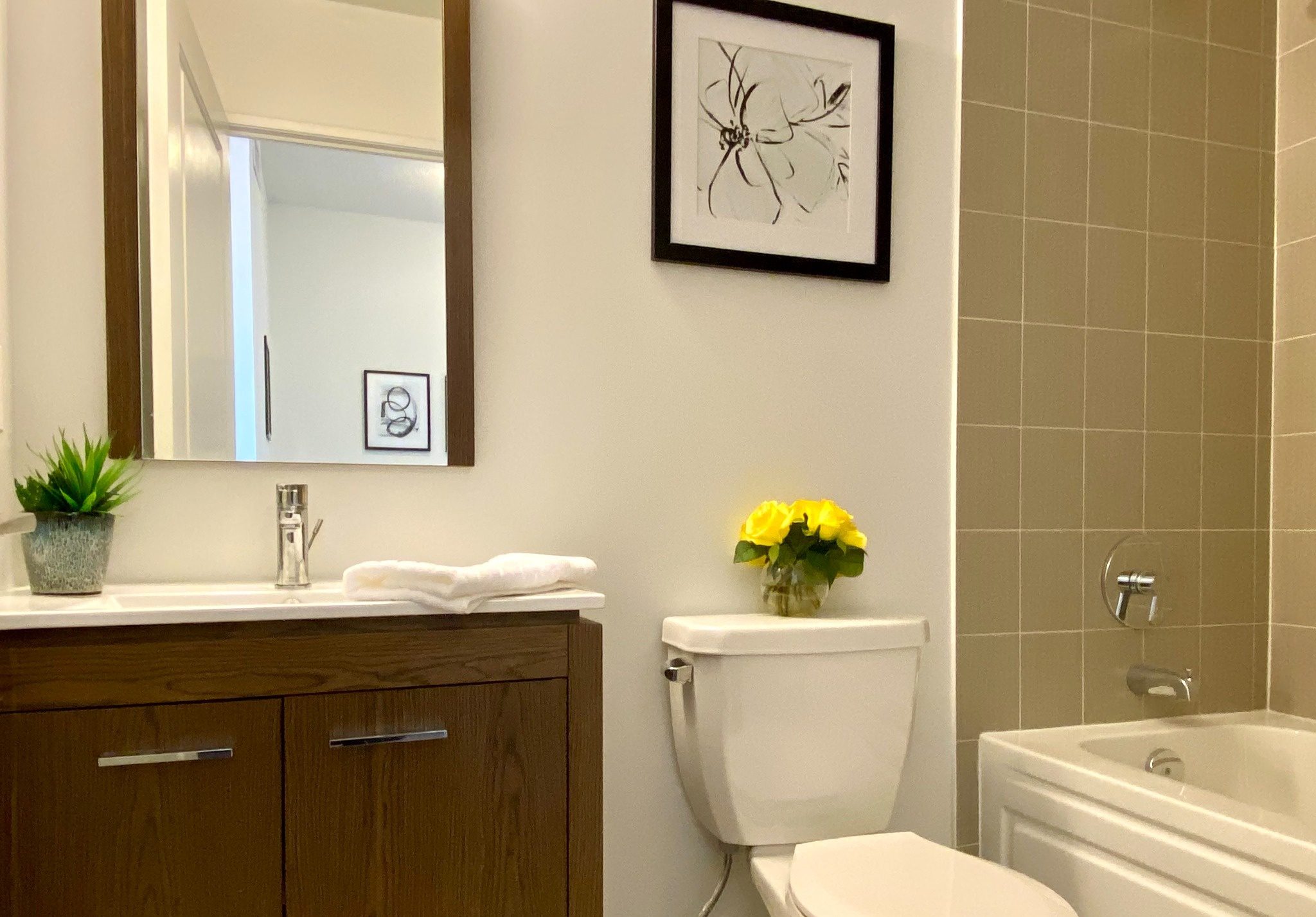 Modern bathroom with wood‑finish vanity and tub.