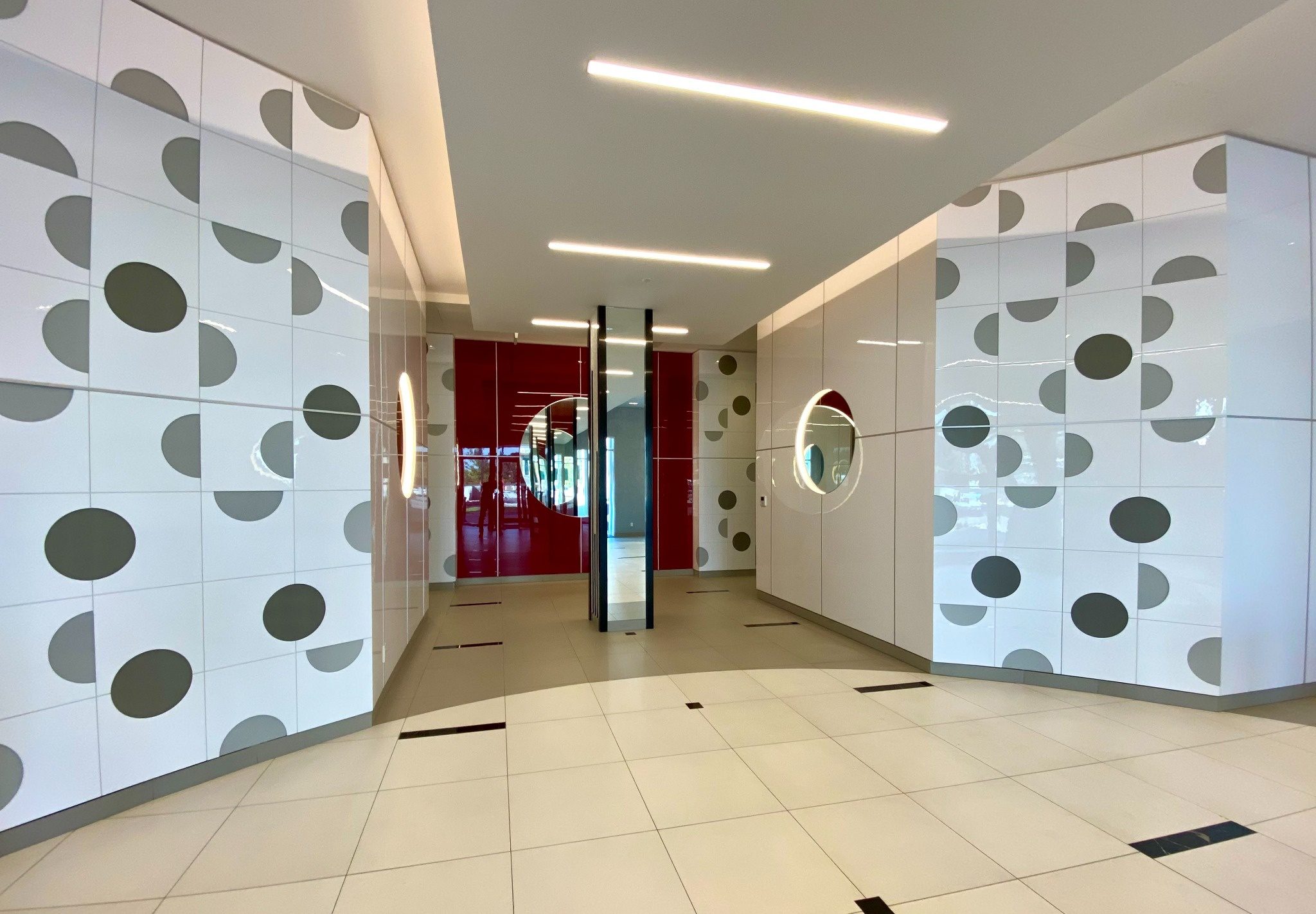 Lobby view with red accent wall and circular mirror design.