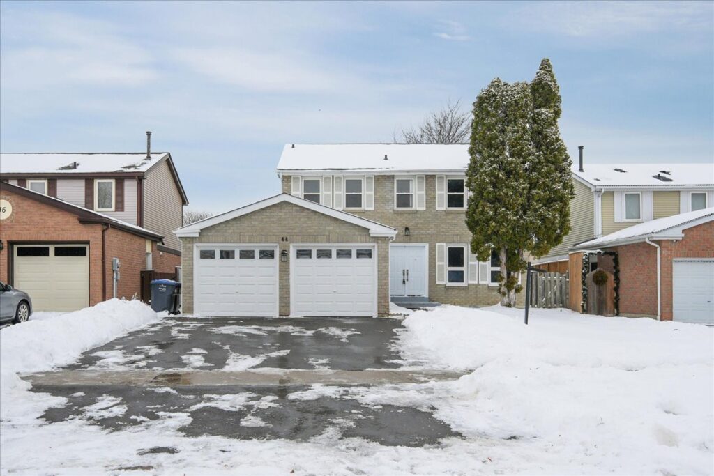 Front exterior of 44 Newcastle Crescent in Brampton featuring a renovated detached home with double garage, new driveway, and mature trees.