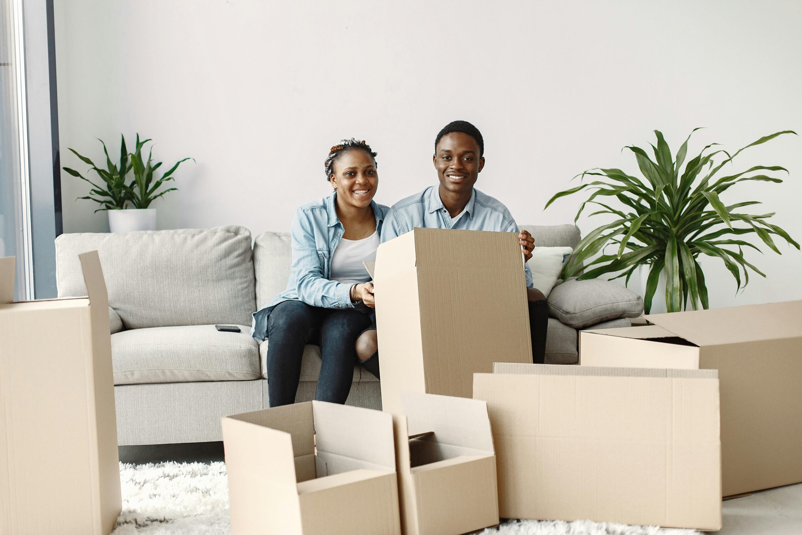 Couple sitting on a couch surrounded by moving boxes during a downsize