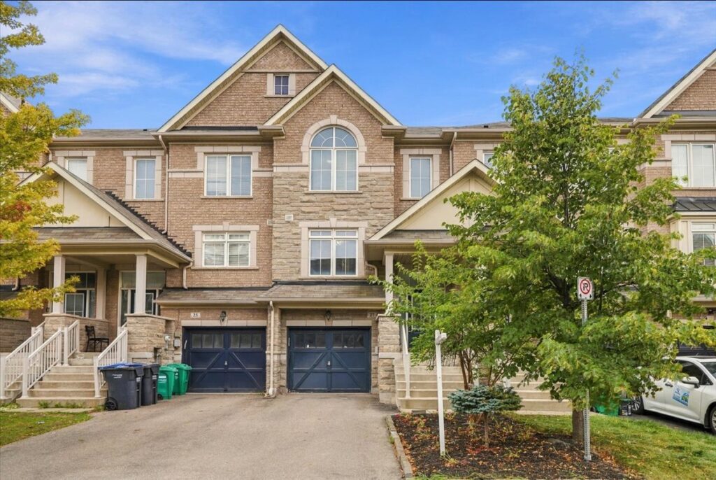 Brampton freehold townhome at 27 Rockbrook Trail with brick and stone front, arched window and single-car garage.